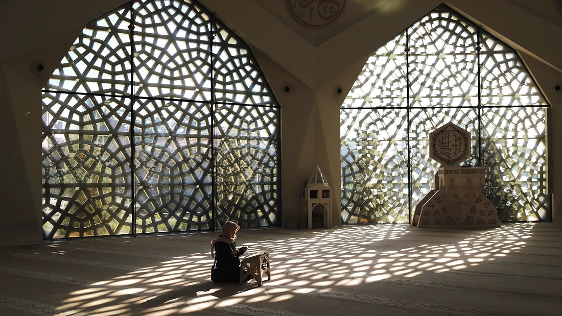 Personne assise lisant le Coran sous les motifs de lumière d'un moucharabieh