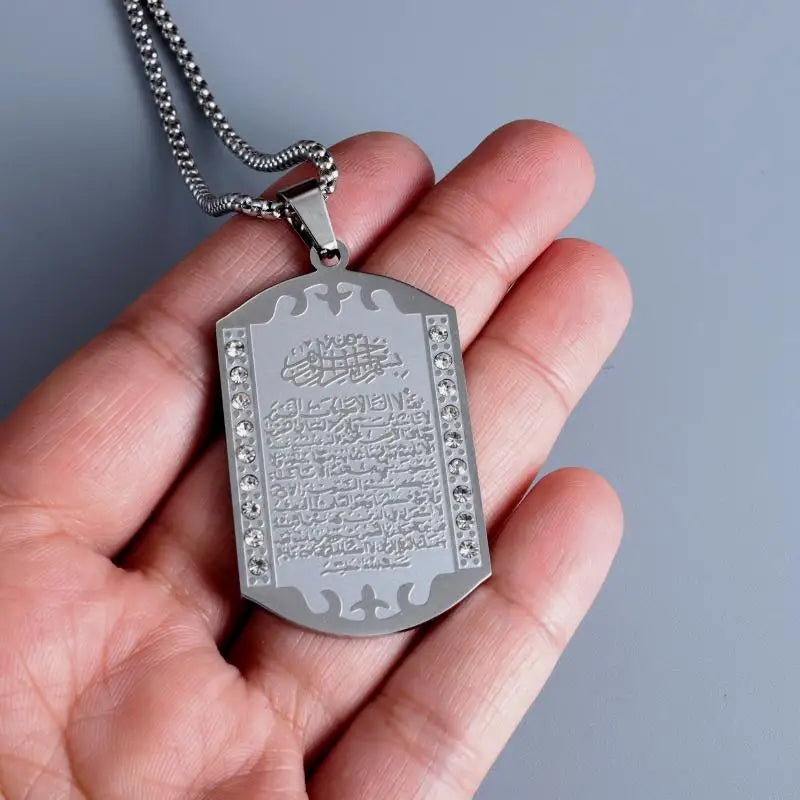 Pendentif Ayat al-Kursi serti de zircons tenu dans la main, pour l'échelle