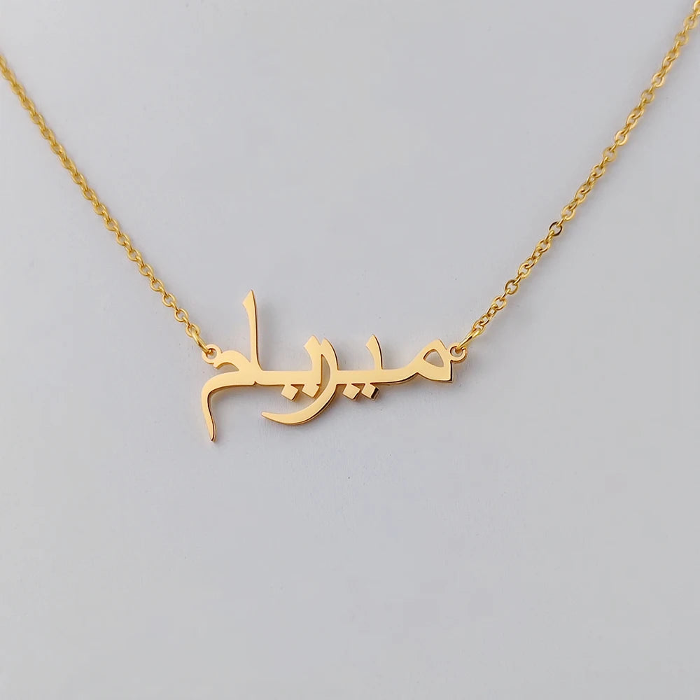 Gros plan sur le pendentif prénom en calligraphie arabe doré